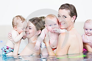 Mothers and their little children having fun at baby swim lesson