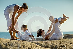 Mothers and their sons are doing yoga exercises at the seashore