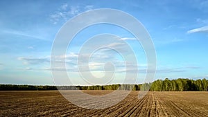 Motion above field with plowed brown soil under blue sky