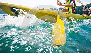 Motion blur, close of explorer women in life jacket paddling hard the kayak with splashes in sunny, adventure in a tropical sea.