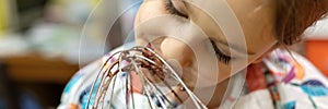 Motion blur effect photo of little kid girl cooking and tastes licks chocolate dough from a whisk for whipping dough at home. dome