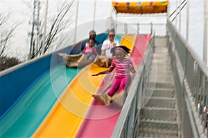 Motion Blur Of Family Sliding Down Fun Slide At Fair