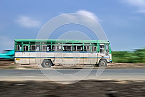 Motion blur image of non air-conditioned intercity bus with blue sky in Maharashtra, speeding on the street.  India.