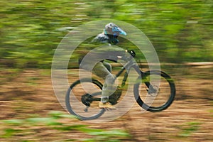 Motion blur, mountain bike and person cycling in forest for adventure, speed and fast power. Athlete, extreme sports and