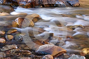 Motion blur photo of water flowing over rounded rocks