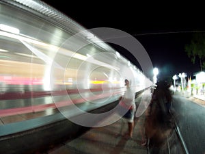 Motion blur shot of fast moving train at night with blur unidentified human figure