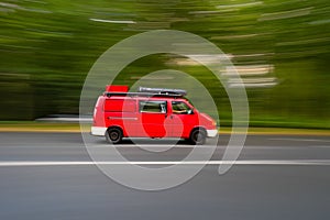 Motion blur shot of a red camper van driving fast in a road