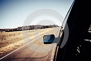 Motion blur view of road with side mirror from inside car