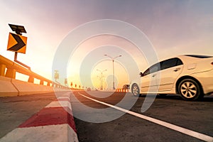 Motion blur of white car driving on curve concrete road with traffic sign. Road trip on summer vacation. Car drive on the street.