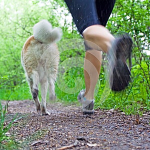 Motion blur of woman running with dog in forest