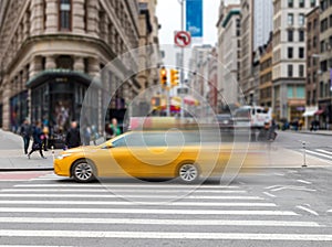 Motion blur of yellow taxi cab speeding through an intersection on 23rd Street in New York City