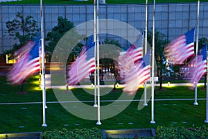 Motion blurred American flags at half mast blowing in the wind in front of a downtown Detroit building