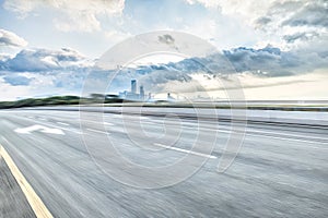 Motion blurred asphalt road and city skyline