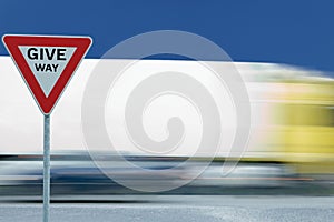 Motion blurred moving truck background, triangular give way text yield traffic sign