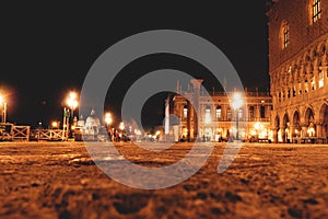 Motion blurred tourists walking along Piazza riva degli Schiavoni along historic buildings at night in Venice, Italy