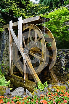 A motion-blurred water wheel with flowers in the foreground