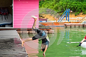 Motion of boy jumping into the lake from the deck