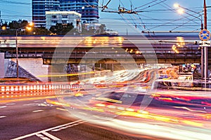 Motion of the cars and train on central city street at evening time.