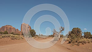 Motion On Dusty Dirt Road In Desert Among Red Rocks Buttes Of Monument Valley