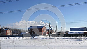 Motion past small village with cottages and steam in winter