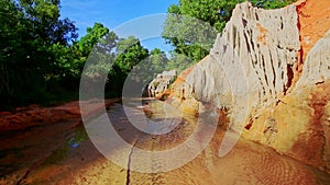 Motion past sunny cliff and shady green banks of fairy stream