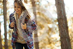 Motion portrait smiling traveler woman in woods with backpack, hiking in forest at autumn.