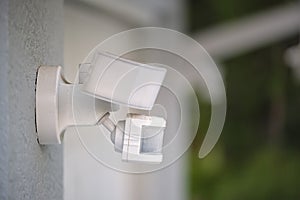 Motion sensor with light detector mounted on exterior wall of private house as part of security system