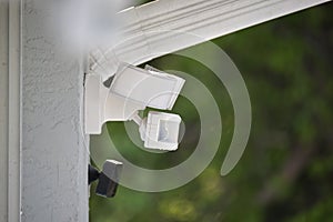 Motion sensor with light detector mounted on exterior wall of private house as part of security system