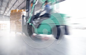 Motion speed blur of forklift driver loading shipment goods into container truck