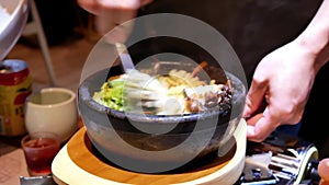 Motion of waiter stirring Korean bibimbap for customer on table