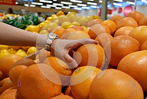 Motion of woman`s hand picking grapefruit inside superstore