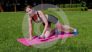 Motivated active sporty fit woman practicing renegade row workout in park
