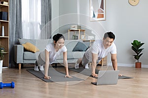 Motivated asian man and woman training at home, using computer