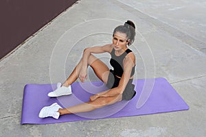 Motivated attractive healthy caucasian sportswoman doing sport exercises using fitness mat, traning quay facing sunrise.