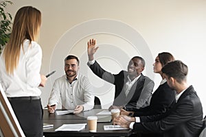 Motivated biracial male employee raise hand answering at team training