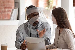 Motivated biracial male student discuss project with female mate