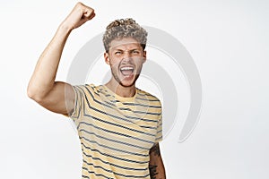 Motivated blond handsome guy rooting, protesting, raising clenched fist and shouting to encourage you, cheering