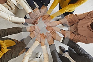 Motivated business people with their hands form circle that symbolizes unity and teamwork.