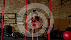 Motivated fitness black female doing cross training with battle ropes in gym