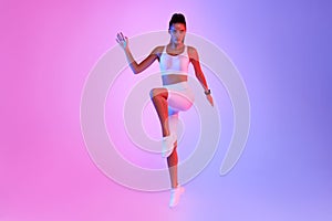 Motivated Fitness Woman Exercising Raising Knee Over Neon Studio Background