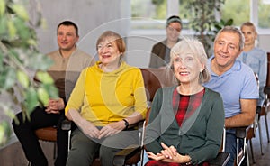 Motivated older woman listening to lecture in group auditorium