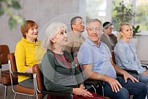 Motivated older woman listening to lecture in group auditorium