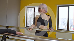 Motivated woman dancer at barre looking with determined stare in mirror