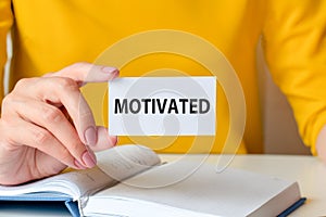 motivated written on a paper card in woman hand, concept