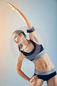 Motivated young sporty woman side bending while warming up