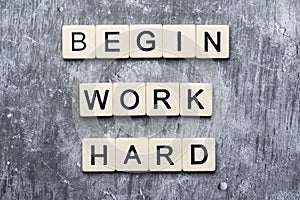 The motivating slogan Begin Work Harder formed with tile letters