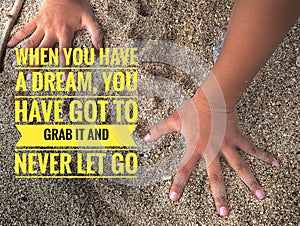 Motivation inspirational quote - When you have a dream, you have got to grab it and never let go. with hand grab sand background
