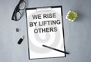 Motivation life quote on notepad - We Rise by Lifting Others