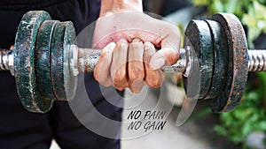Motivation quote - No pain, no gain. With person holding dumbbell in hand, lifting weights.