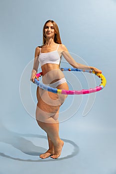 Motivation to be beautiful and healthy. Young slim girl with plus-size woman& x27;s body doing exercises with hoop